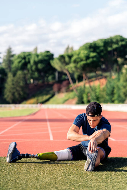 Disabled man athlete stretching with leg prosthesis. Paralympic Sport Concept. - Foto, imagen