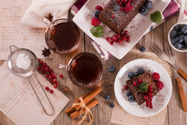 Chocolate sponge cake with fresh fruit on white dish. - Foto, Imagen