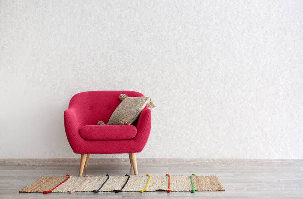 Viva magenta πολυθρόνα με μαξιλάρι και χαλί κοντά σε λευκό τοίχο στο δωμάτιο. Banner για το σχεδιασμό - Φωτογραφία, εικόνα