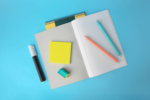 Flat lay composition with erasable pens and copybook on light blue background - Foto, imagen
