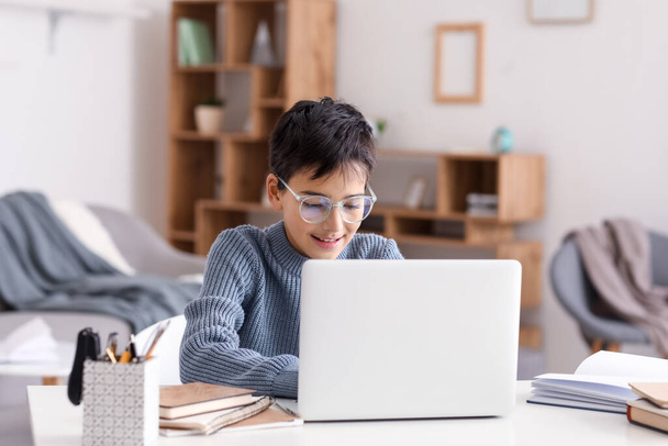 Маленький мальчик в очках с ноутбуком дома - Фото, изображение