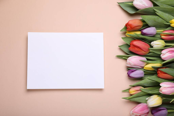 Beautiful tulips and blank card on pale pink background, flat lay - Photo, Image