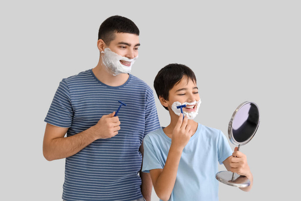 Father and his little son with mirror shaving against light background - 写真・画像