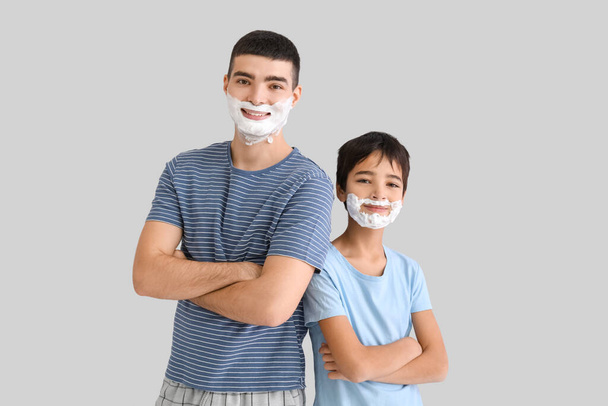 Батько і його маленький син з піною для гоління на обличчях на світлому фоні
 - Фото, зображення
