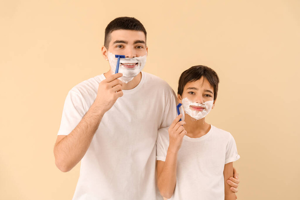 Father and his little son shaving against beige background - Foto, Imagen