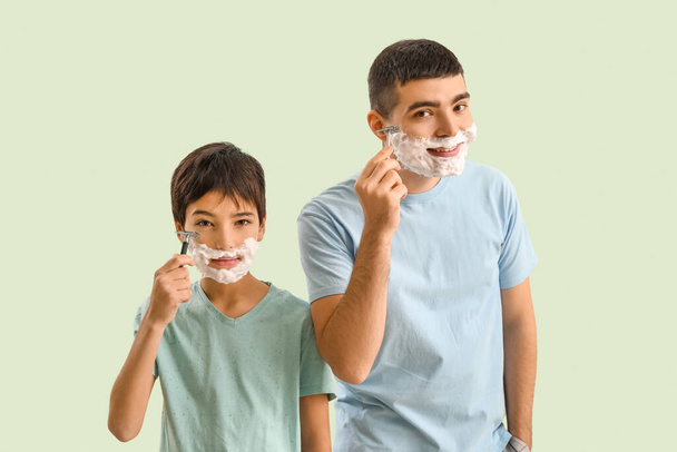 Man and his little son shaving against light color background - Foto, imagen
