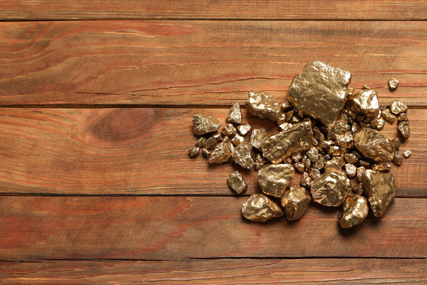 Pile of shiny gold nuggets on wooden table, flat lay. Space for text - Valokuva, kuva