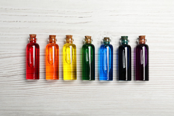Glass bottles with different food coloring on white wooden table, flat lay - Zdjęcie, obraz