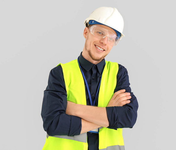 Male worker in vest and hardhat on grey background - Foto, Bild
