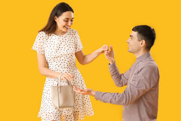Charmant jeune couple tenant la main sur fond jaune - Photo, image