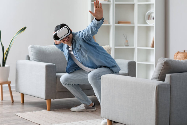 Young man using VR glasses at home - Foto, Imagen