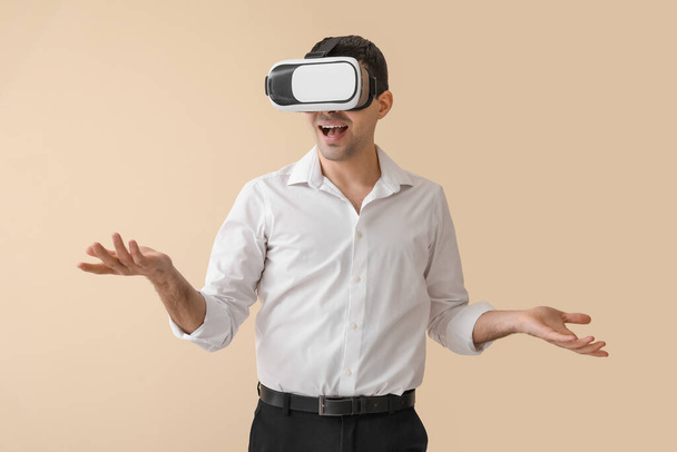 Young man using VR glasses on beige background - Zdjęcie, obraz