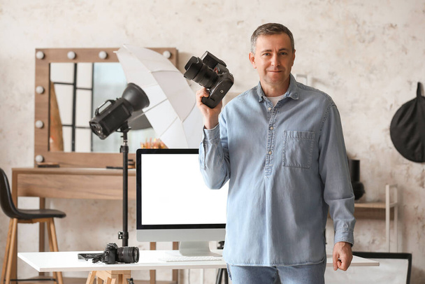 Зрелый фотограф с профессиональной камерой в студии - Фото, изображение