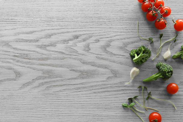 Fotografía de comida. Tomates cherry frescos, brócoli, ajo y microverde sobre mesa de madera, plano con espacio para el texto - Foto, imagen