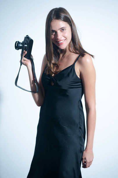 Portrait of pretty young woman with photo camera of photographer. Portrait of a sensual girl with a camera in hand on a white background. Isolated studio - Foto, Bild