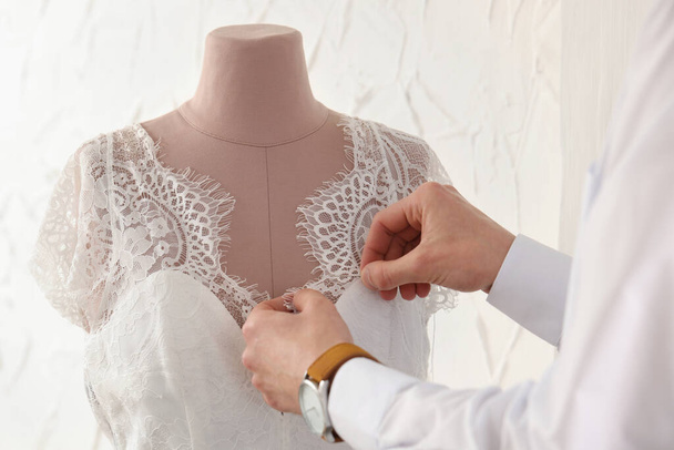 Dressmaker working with wedding dress on mannequin in atelier, closeup - Foto, afbeelding