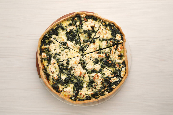 Delicious homemade spinach quiche on white wooden table, top view - Foto, imagen