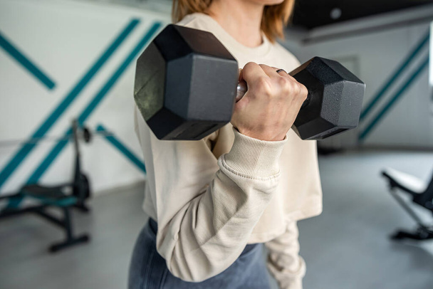 Mujer de fitness en entrenamiento con pesas grandes para deportes. Una muestra de cerca de manos fuertes. cuerpo sano - Foto, imagen