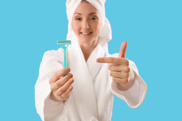 Csinos fiatal nő borotvával kék háttér - Fotó, kép