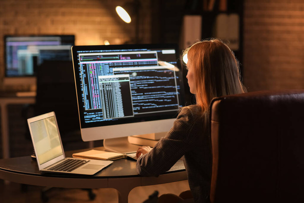 Vrouwelijke programmeur werkt 's nachts met computer op kantoor - Foto, afbeelding