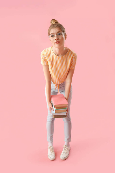 Jeune femme bouleversée avec des livres sur fond rose - Photo, image