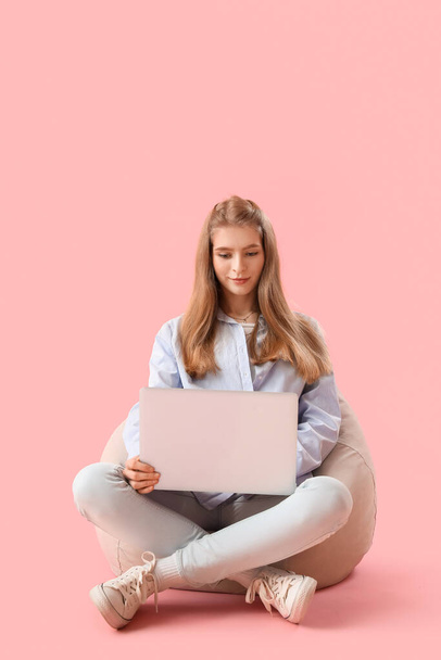 Женщина-программист работает с ноутбуком на розовом фоне - Фото, изображение