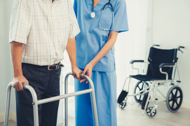 Physiotherapist assists her contented senior patient on folding walker. Recuperation for elderly, seniors care, nursing home. - Valokuva, kuva