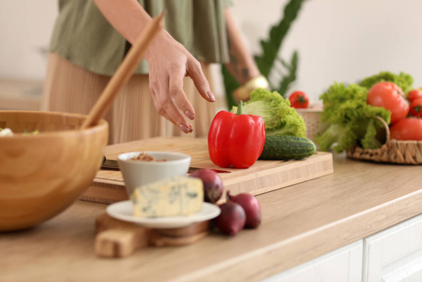 Зрелая женщина делает овощной салат за столом на кухне, крупным планом - Фото, изображение