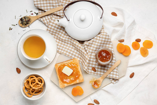 Toast savoureux avec confiture d'abricot, biscuits et tasse de thé sur fond clair - Photo, image