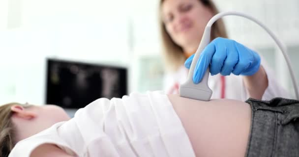 Dokter kinderarts uitvoeren van abdominale echografie onderzoek van de interne organen van het kind in kliniek 4k film slow motion. Diagnose van de behandeling van ziekten van het maagdarmkanaal bij kinderen - Video