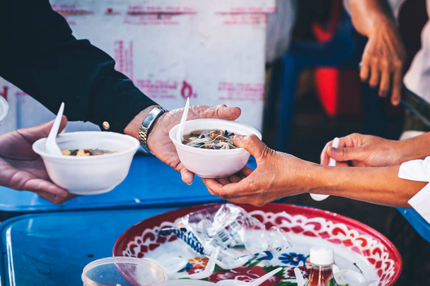 Volunteers serving hot meals to hungry migrants: humanitarian aid concept. - Фото, изображение