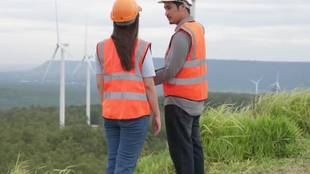 Mužští a ženské inženýři pracující na větrné farmě na vrcholu kopce nebo hory na venkově. Progresivní ideál pro budoucí výrobu obnovitelné, udržitelné energie. - Záběry, video