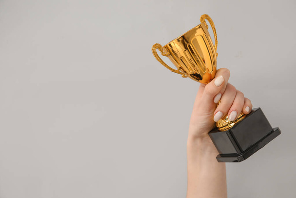 Woman with gold cup on grey background - Photo, Image