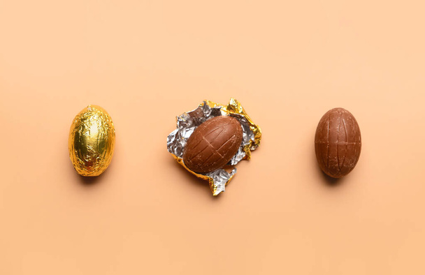 Schokoladen-Ostereier in Goldfolie auf beigem Hintergrund - Foto, Bild