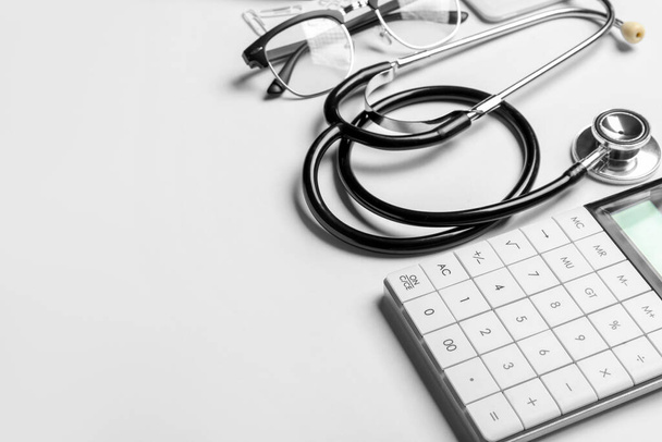 Stethoscope, calculator and glasses on white background - Photo, Image