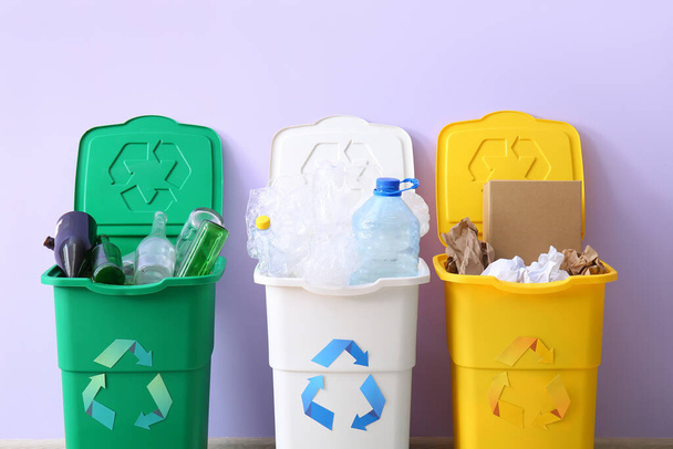 Containers with different types of garbage on lilac background. Recycling concept - 写真・画像