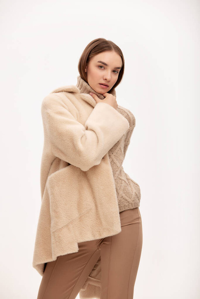 Close-up of a modern business woman on a light background in fashionable faux fur clothes, fashion, modern urban style. - Photo, image
