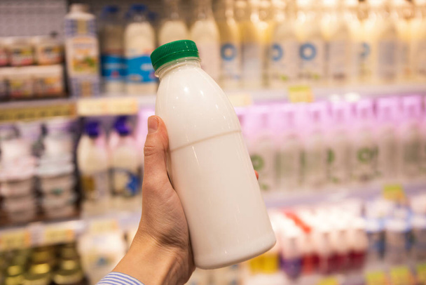 Female hand holds blank bottle of dairy product - Foto, Imagen