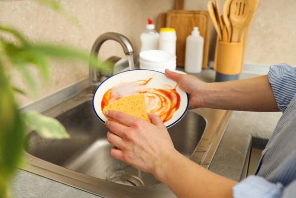 女性の手はシンクで皿を洗う - 写真・画像