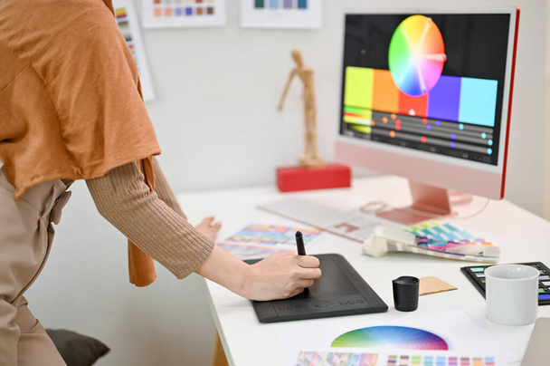 Oříznutý obrázek ženského grafického designu pomocí grafického tabletu a stylusu, pracující na svém novém projektu v kanceláři. - Fotografie, Obrázek