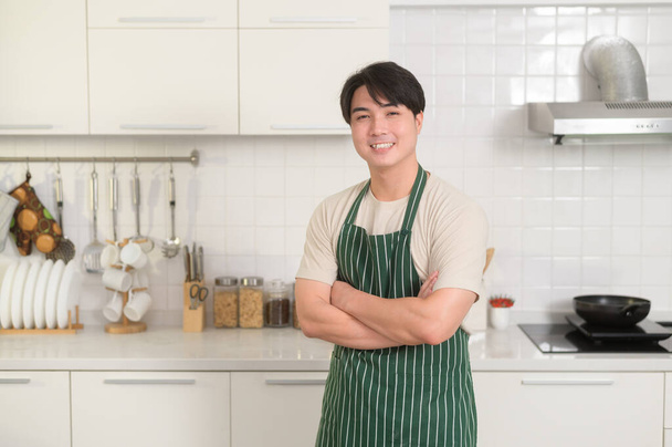 portrait of smart young Asian man smiling  in kitchen at home - Foto, immagini