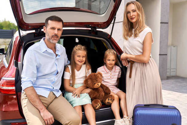 Araba yolculuğundan önce dört kişilik beyaz bir ailenin portresi. - Fotoğraf, Görsel