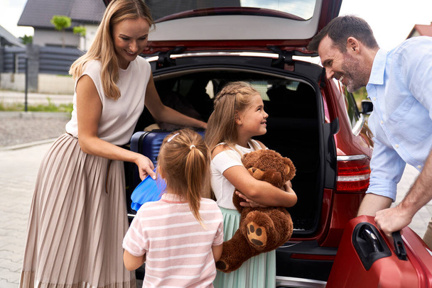 Valkoihoinen perhe neljän pakkaus matkatavarat auton takakonttiin loma - Valokuva, kuva