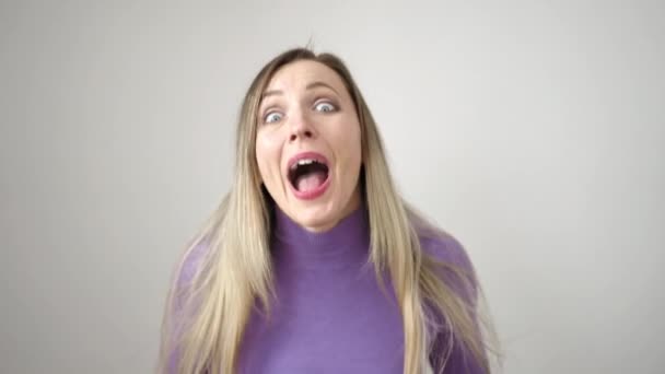 jonge blonde vrouw staan met verrassing uitdrukking over geïsoleerde witte achtergrond - Video