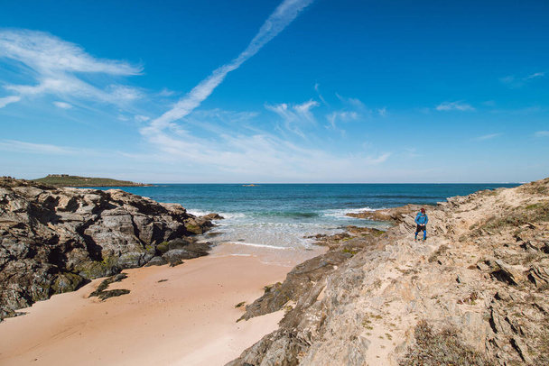 Hátizsákos sétál végig egy szikla és a homokos tengerparton a megjelölt halászati útvonal az Atlanti-óceán partján közelében Porto Covo, Portugália. Rota Vicentina. - Fotó, kép
