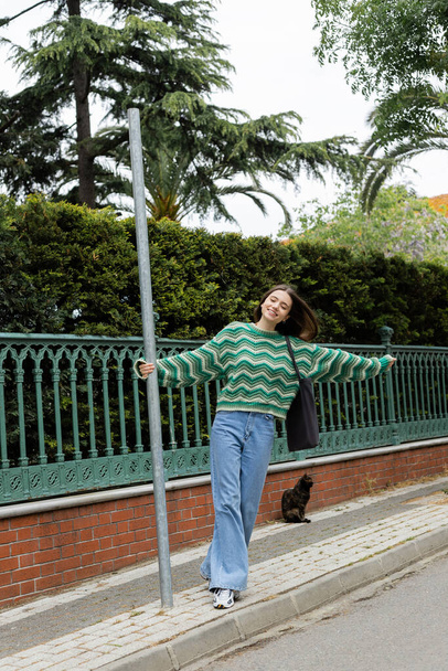 Positieve vrouw in trui en jeans loopt op straat in Istanbul  - Foto, afbeelding