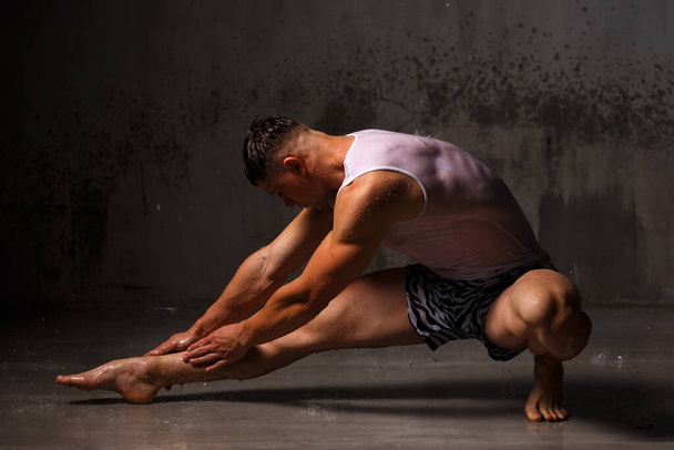 Bodybuilder flaunts his muscles and figure in the studio in the rain. - Foto, Imagen