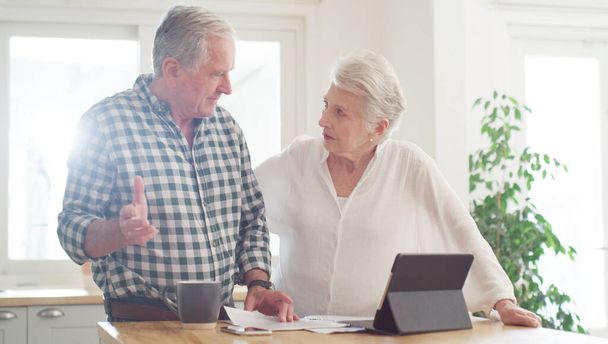 Invece di uscire, possiamo farlo online. una coppia di anziani che usa un tablet digitale mentre scorre le scartoffie a casa - Foto, immagini