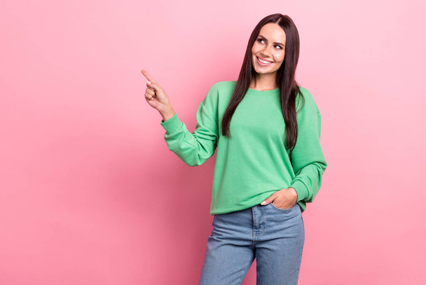 Portrait of positive cute person long hairstyle wear green pullover indicating look at offer empty space isolated on pink color background. - Foto, Imagem