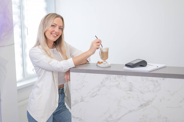 Female client of a beauty salon drinking coffee at the reception desk - Foto, Imagem